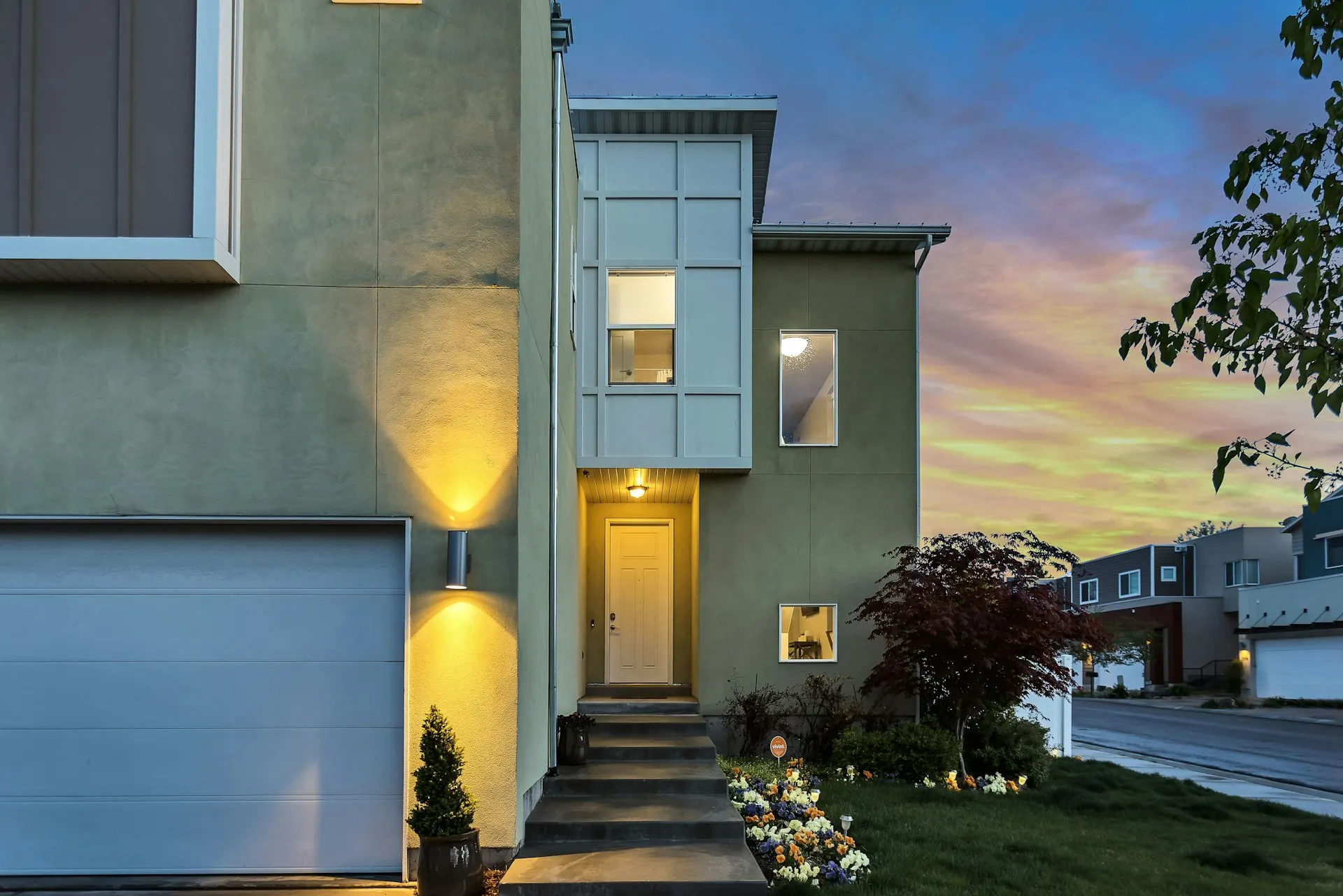 Front of a modern home at dusk with lit windows