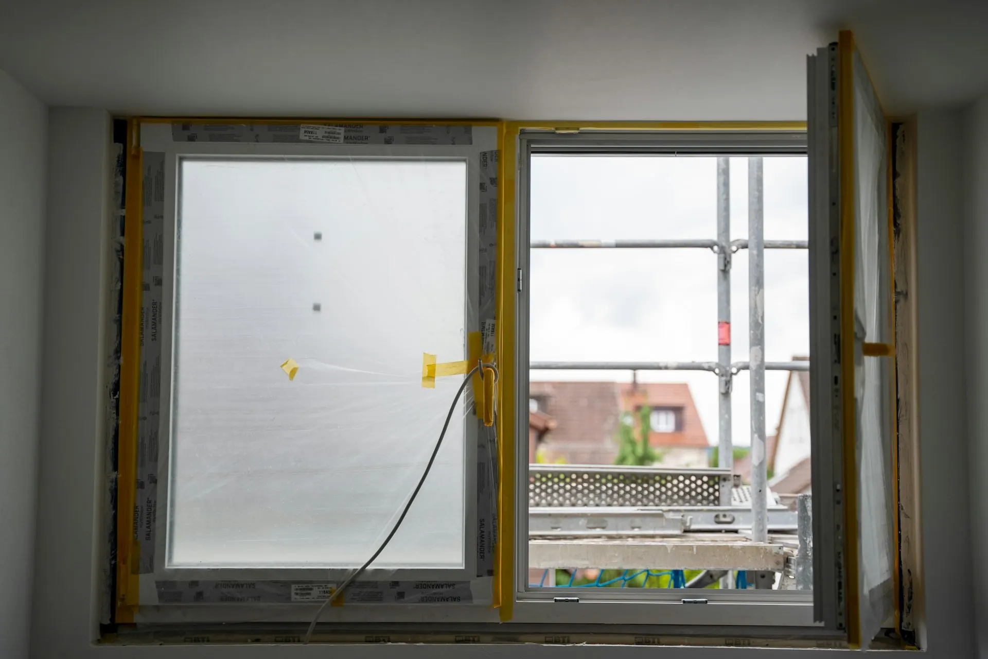 New window being installed in an opening, with the old frame taped off
